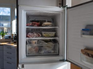 Öppen frys med frost på insidan i ett vanligt skandinaviskt kök