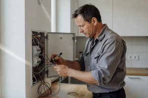 Elektriker kontrollerar säkringsbox för att förhindra elöverbelastning i hemmet