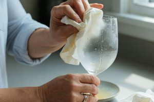 Kvinna gnuggar grumligt glas med ättikaduk i kök