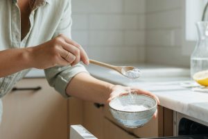 Kvinna häller bikarbonat i öppet diskmedelsfack