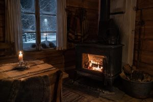 Vedkamin brinner i mörkt hus under snöstorm och strömavbrott
